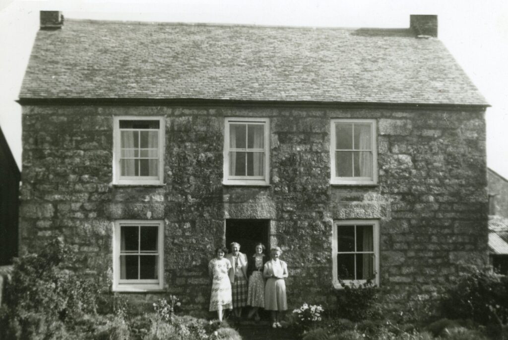 A Picture of an old stone house with ladies in the front door