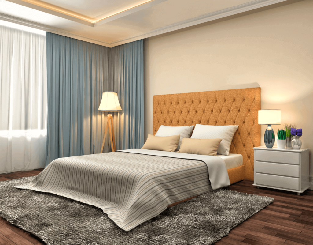 Cozy bedroom setup with a mustard tufted headboard, grey bedding, a textured rug, and light blue curtains.