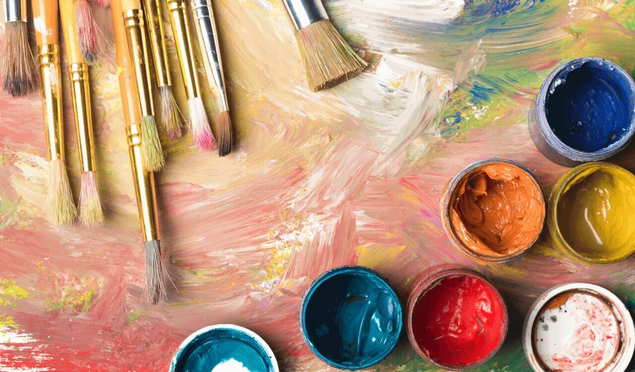Artist's palette with brushes and open paint jars in vibrant colors.